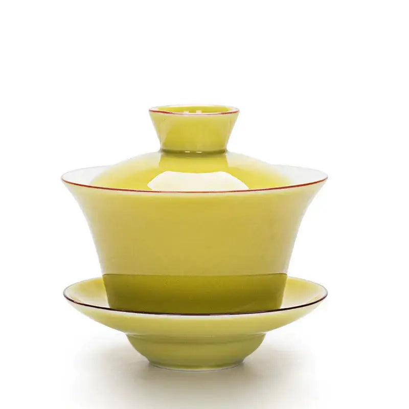 A glossy lime green ceramic gaiwan with thin red rims paired with a celadon tea tureen featuring gold rim accents