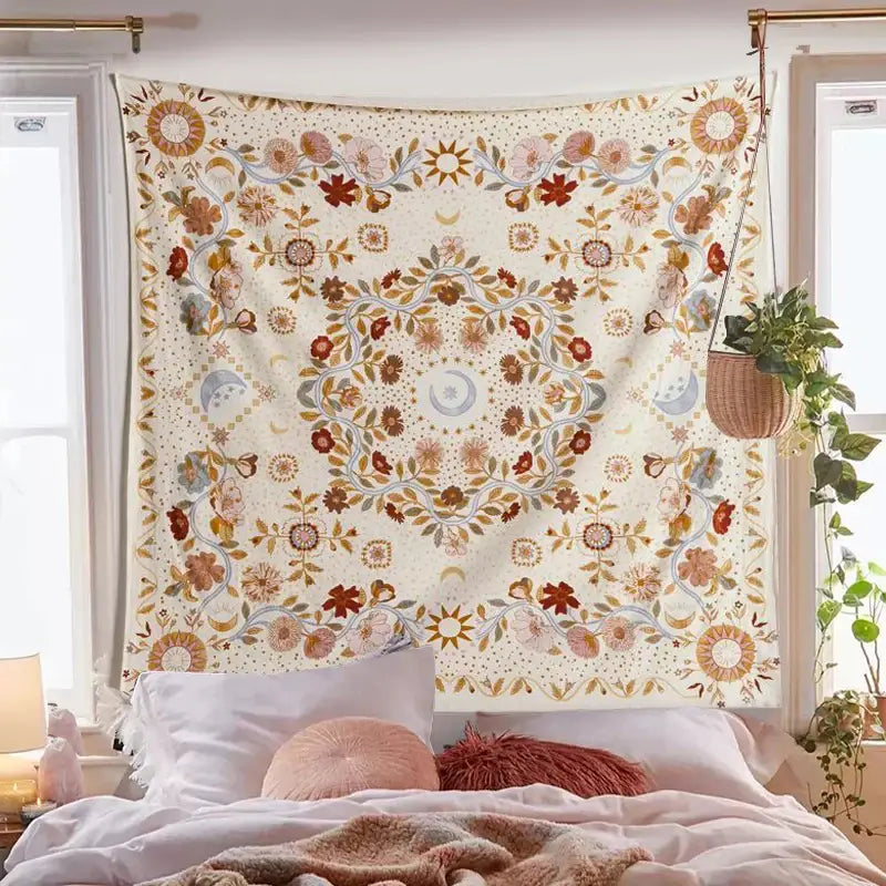 A cream-colored decorbites celestial floral moon phase tapestry with rust gold and muted blue hangs above a bed