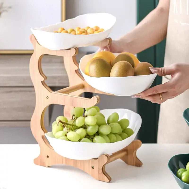Three-tiered wooden fruit stand with white ceramic bowls part of ceramic and teal 3-layer table plates set for dining room