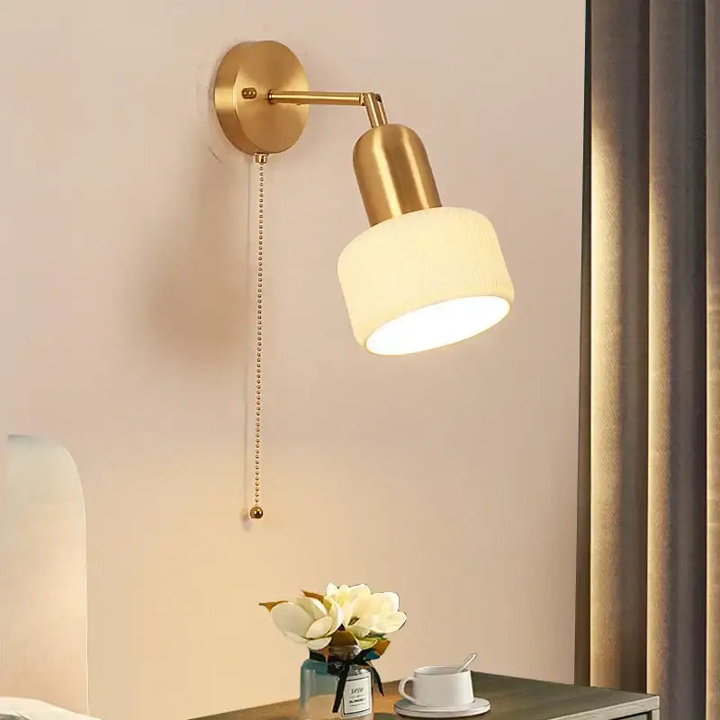 Gold-finished ceramic art wall lamp with frosted white cylindrical shade and adjustable arm for bedroom reading light