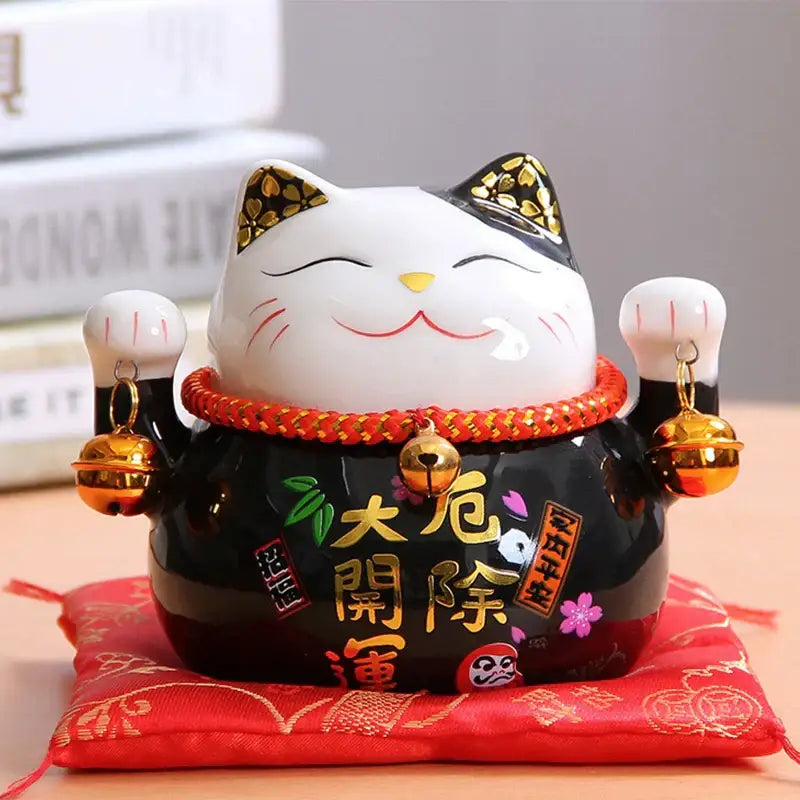 Ceramic maneki neko piggy bank in white and black ceramic with gold accents red rope collar and golden bells decorbites ceramic maneki