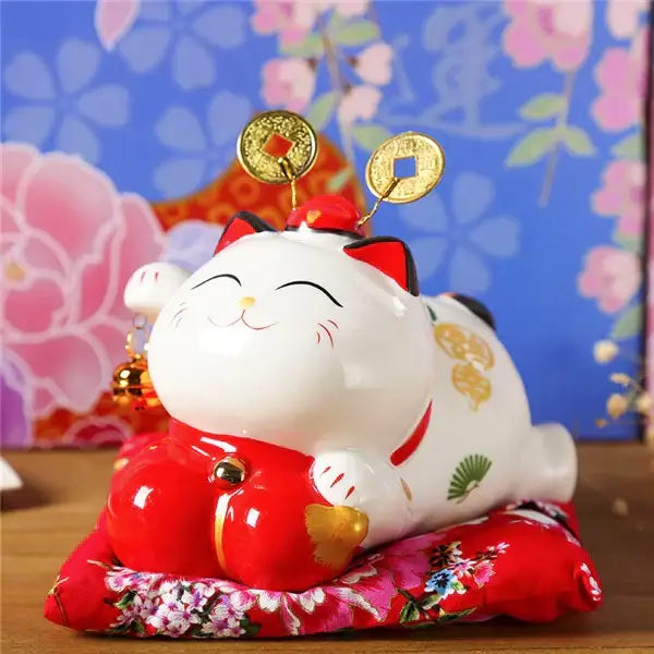 Ceramic maneki neko piggy bank in white ceramic with red accents and gold coin details for living room decor
