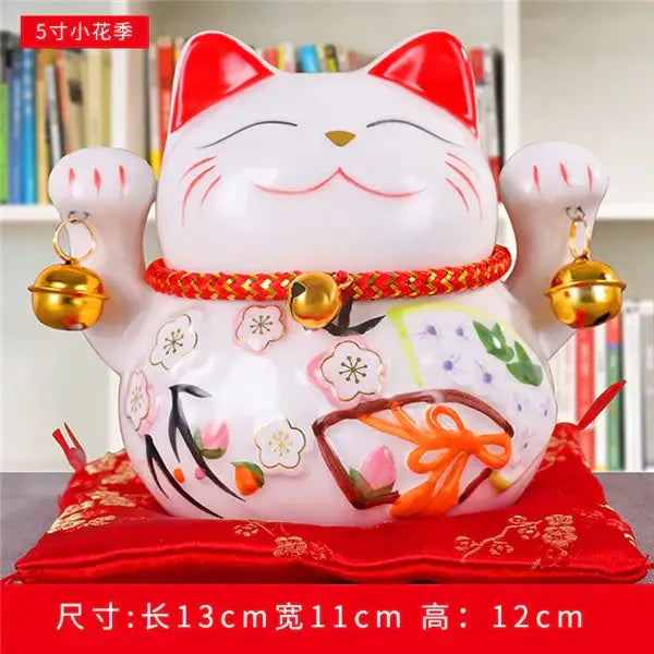 White ceramic maneki neko piggy bank with red floral accents and gold bells decorbites ceramic maneki living room decor