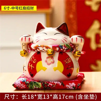 White ceramic maneki neko piggy bank with red accents gold bells and floral sash for decorbites ceramic maneki decor