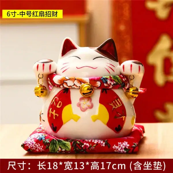White ceramic maneki neko piggy bank with red accents gold bells and floral sash for decorbites ceramic maneki decor