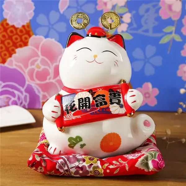 White ceramic maneki neko piggy bank with red accents holding a scroll and gold coins decorbites ceramic maneki decor