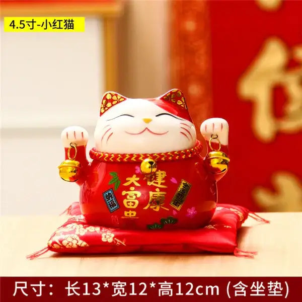 Red ceramic maneki neko piggy bank with gold accents and chinese characters on matching red cushion decorbites ceramic maneki