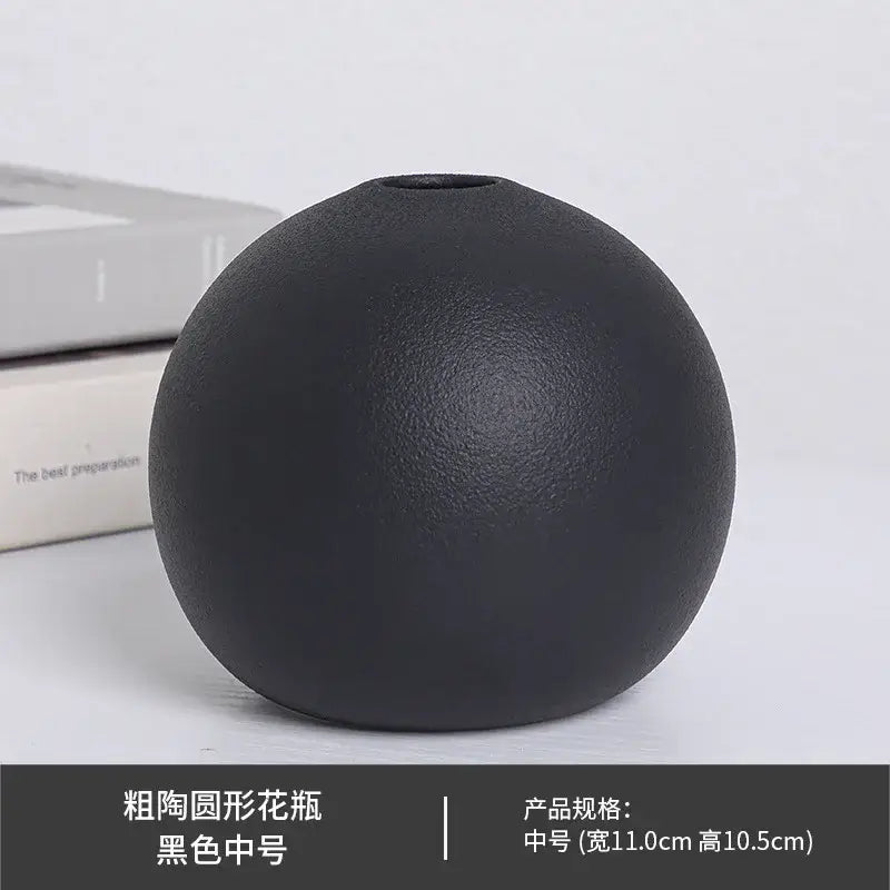 A ceramic round vase black white with a matte black textured surface and a small top opening