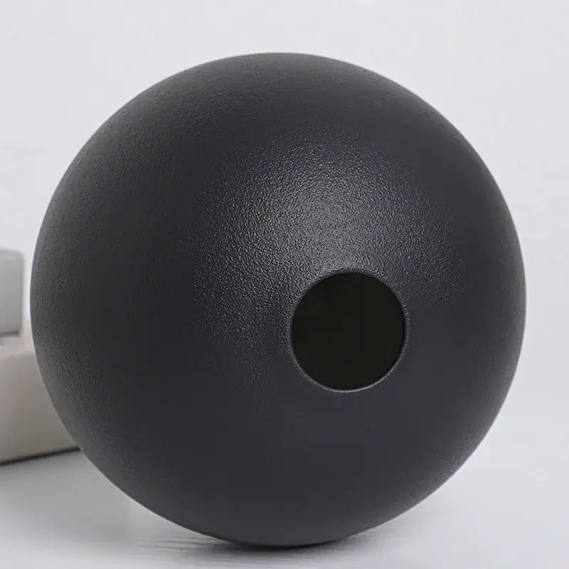A matte black textured ceramic round vase black white with a central circular opening for decorative use