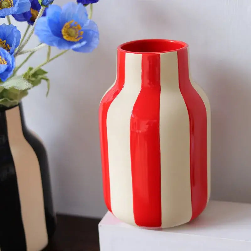 A glossy red striped ceramic vase with cream vertical stripes and a rounded bulbous body for decorative use