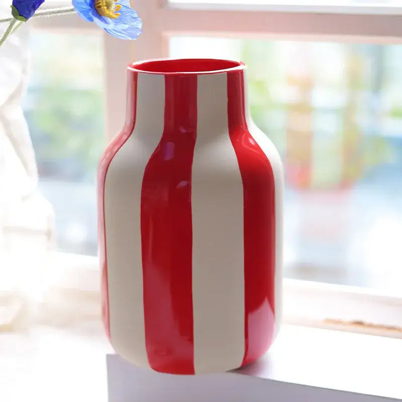 A glossy red and white striped ceramic vase with a rounded body and narrow neck for decorative use