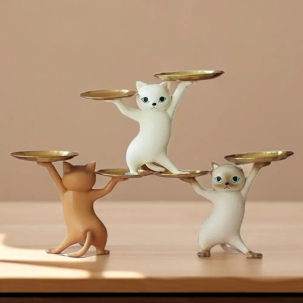 Ceramic white and beige cat figurines with blue eyes balancing golden trays serve as elegant cat figurines storage trays