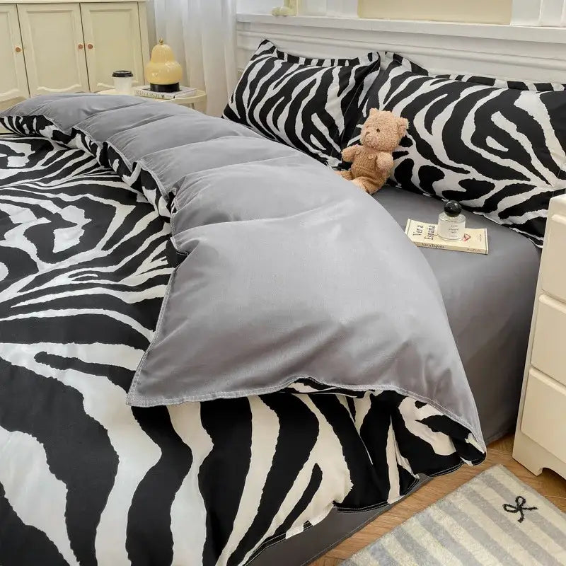 Gray zebra-print duvet cover set with plush teddy bear on bed in checkerboard black and beige satin bedroom bedding