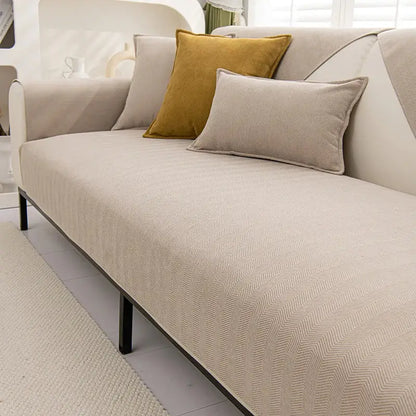 Beige chenille textured non-slip herringbone sofa cover with matching sofa cushions and black metal legs for living room use