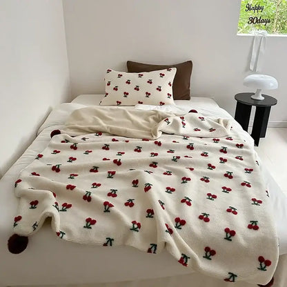 Cream sheep rollie loop fleece blanket with red cherry embroidery green stems and pom-poms at corners for bedroom use