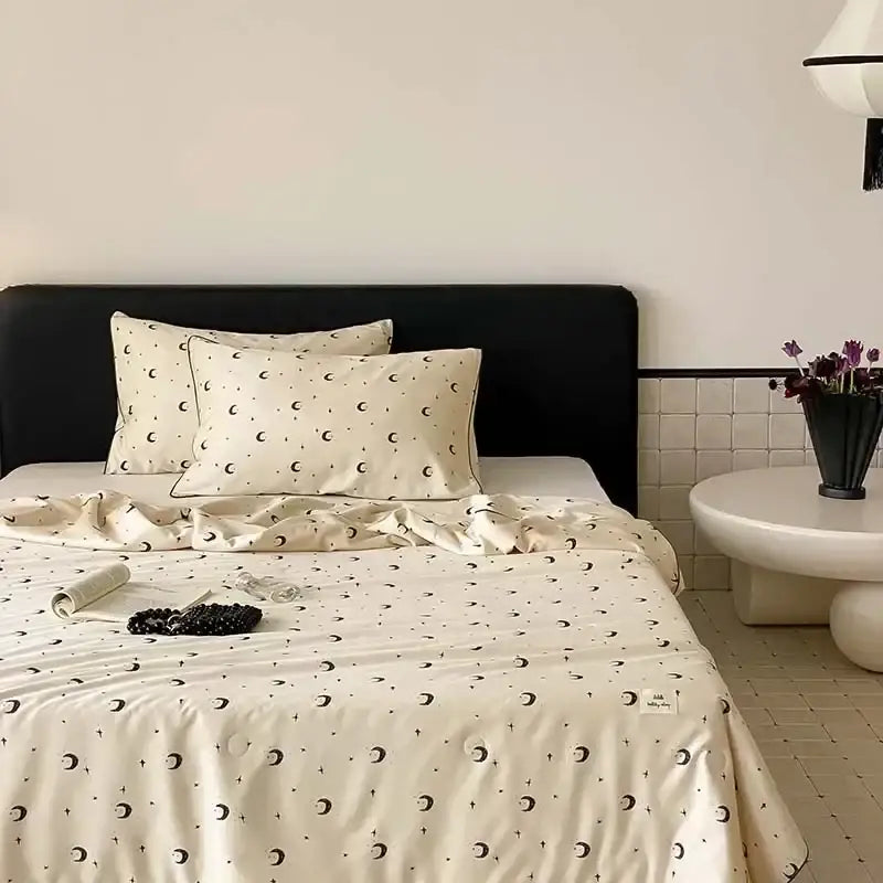 Cream-colored satin cooling quilt with black crescent moons and stars for a comfortable night’s sleep by decorbites
