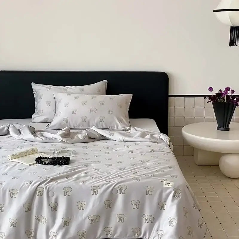 Light gray satin bedding set with subtle dark gray elephant pattern paired with cherry embroidery white and red decorbites cooling quilt for a restful night’s sleep