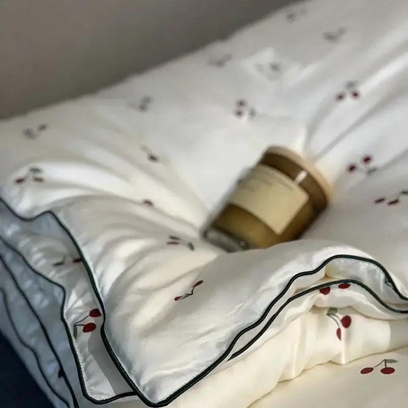 White silk cooling quilt with red cherry embroidery and black piping for a decorbites cooling quilt night’s sleep