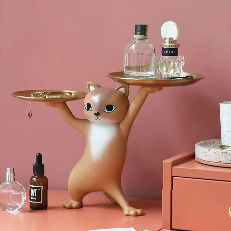 A chic cream and gold decorbites cat resin tray featuring a tan and white ceramic cat figurine with blue eyes balancing trays