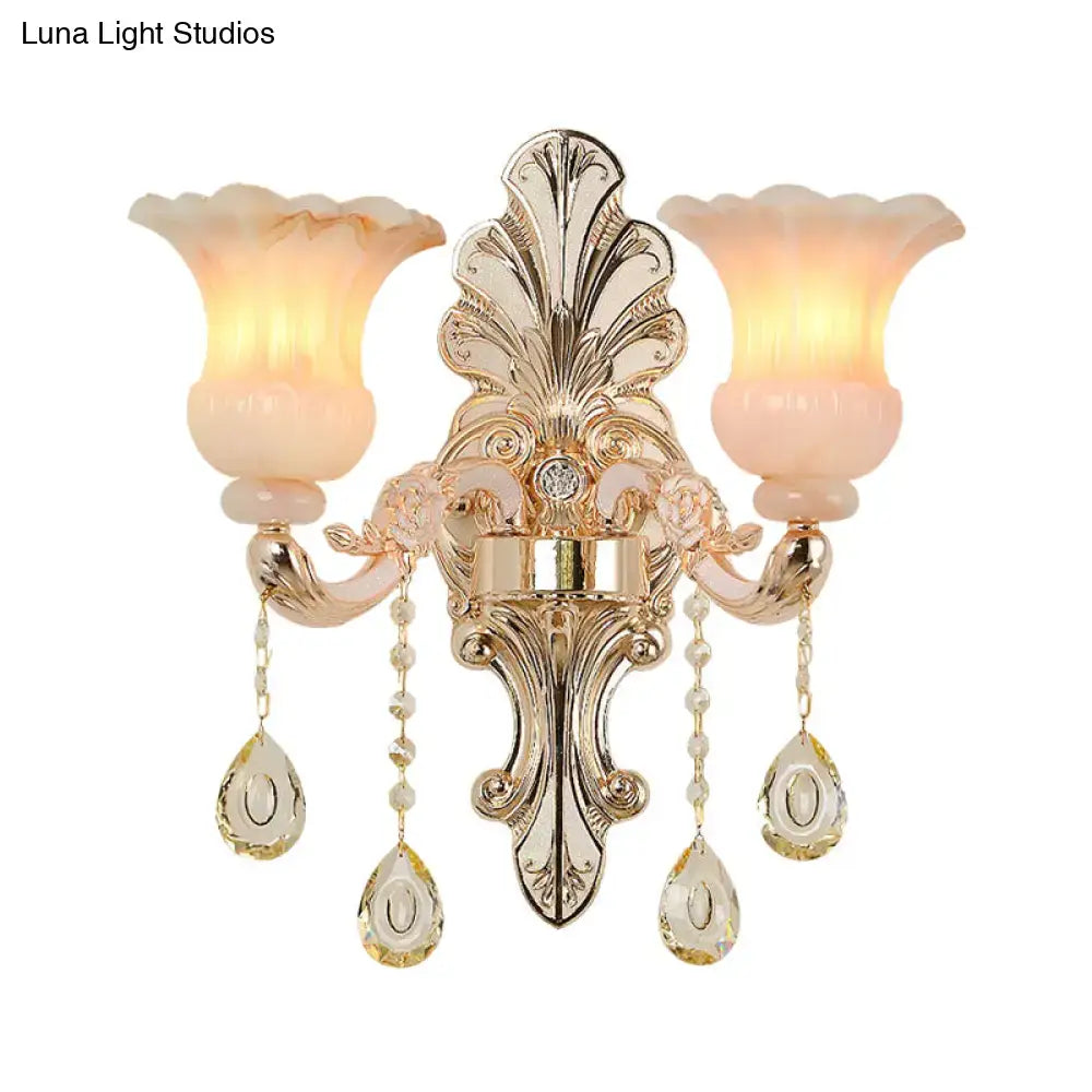 Chic gold wall lamp with peach glass shades and pink crystal teardrop pendants for elegant bedroom decor