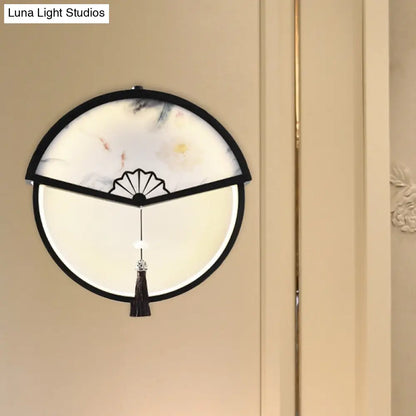 Lámpara de pared LED china de metal negro en forma de abanico con mural de escena de montaña y detalle de borla.
