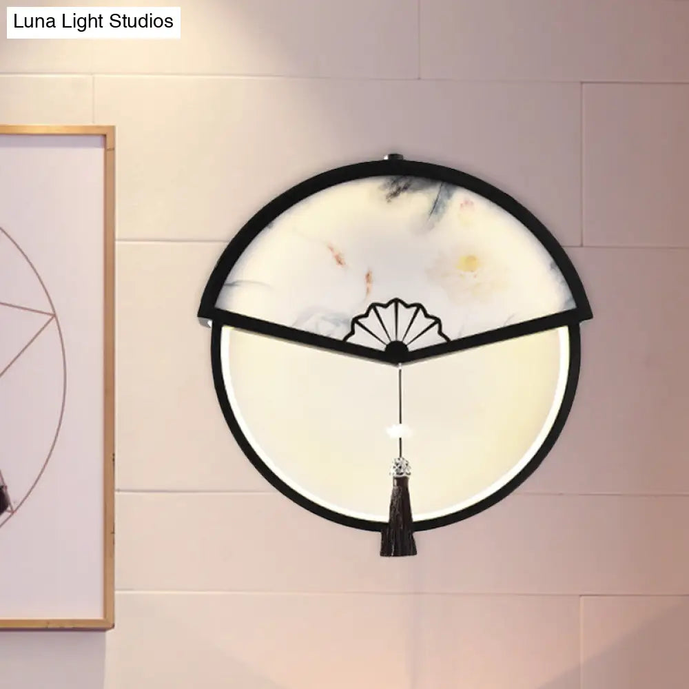 Lámpara de pared LED china de metal negro en forma de abanico con mural de escena de montaña y detalle de borla.