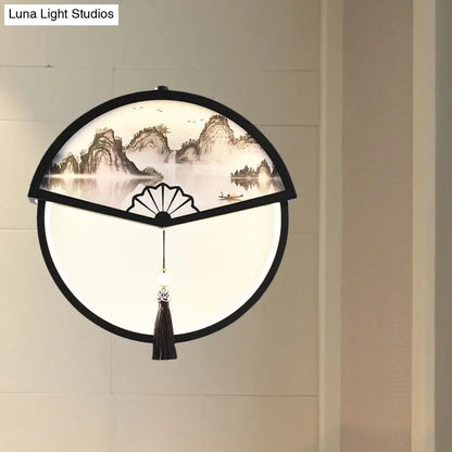 Lámpara de pared LED china de metal negro en forma de abanico con mural de escena de montaña y detalle de borla.