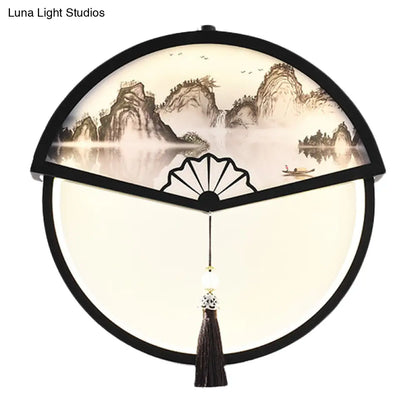 Lámpara de pared LED china de metal negro en forma de abanico con mural de escena de montaña y detalle de borla.