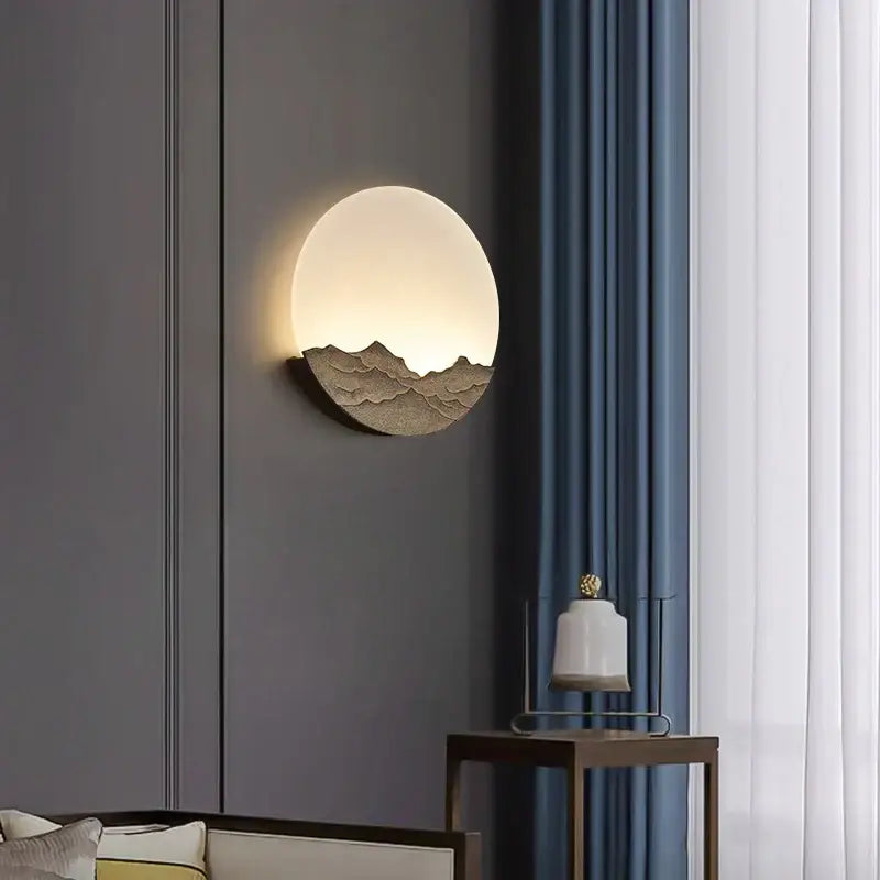 Circular wall light with embossed Chinese mountain design in matte gold-toned metal warm glow decorbites led wall light