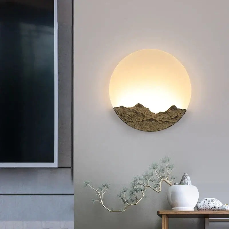 Circular wall light with embossed Chinese mountain design in bronze and gold textured metal decorbites led wall fixture