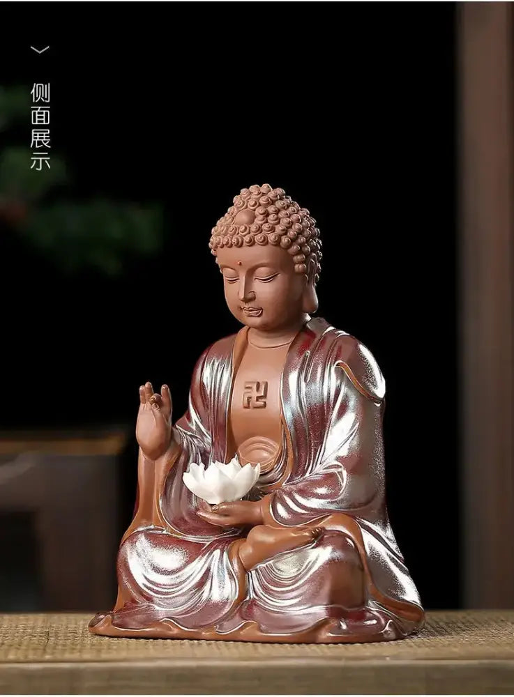 Glossy terracotta ceramic sakyamuni buddha statue seated in meditation holding white lotus with metallic robes for living room