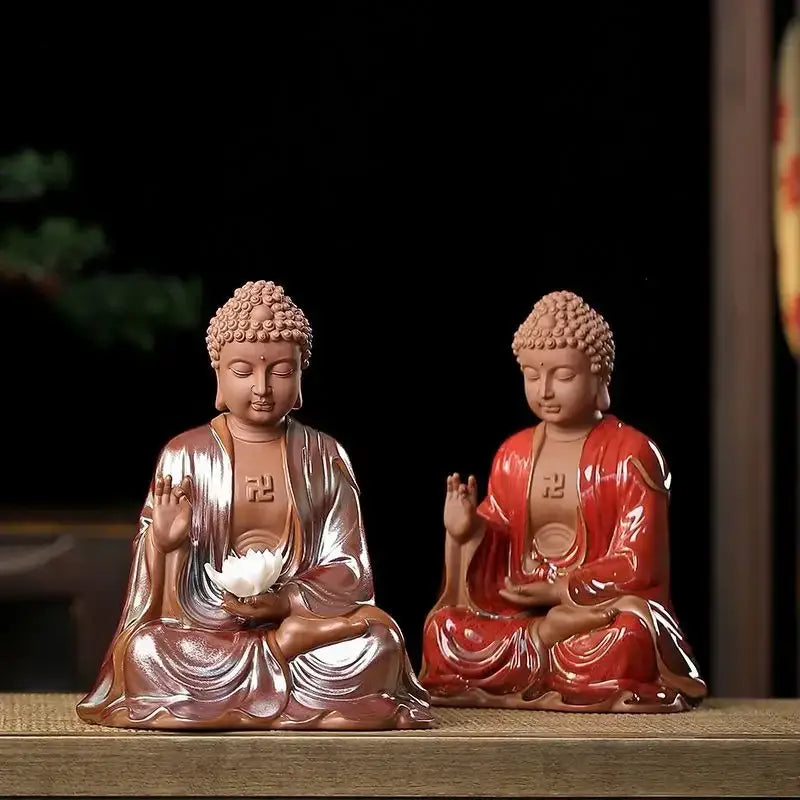 Two ceramic sakyamuni buddha statues in bronze and glossy red finish seated holding lotus flowers for living room