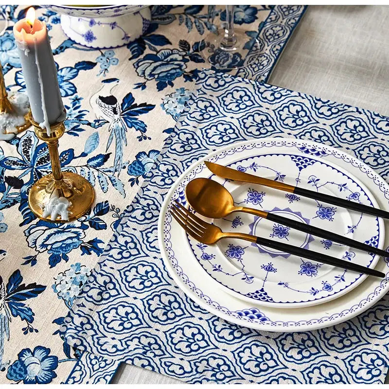 Chinoiserie blue and white porcelain table runner with tassels paired with blue white porcelain dinnerware and gold cutlery