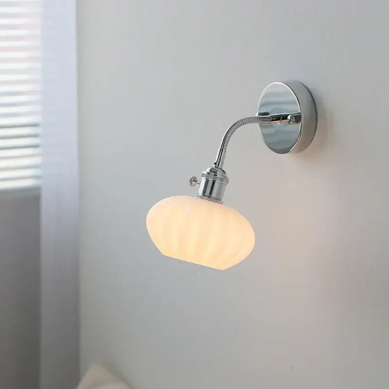 A sleek chrome adjustable arm wall lamp with a flexible gooseneck and off-white ribbed glass shade by decorbites