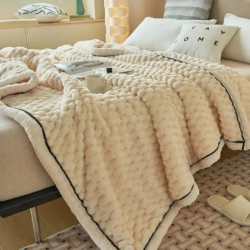 Chunky knit cream and black coral fleece blanket with plush texture and black piping for bedroom use