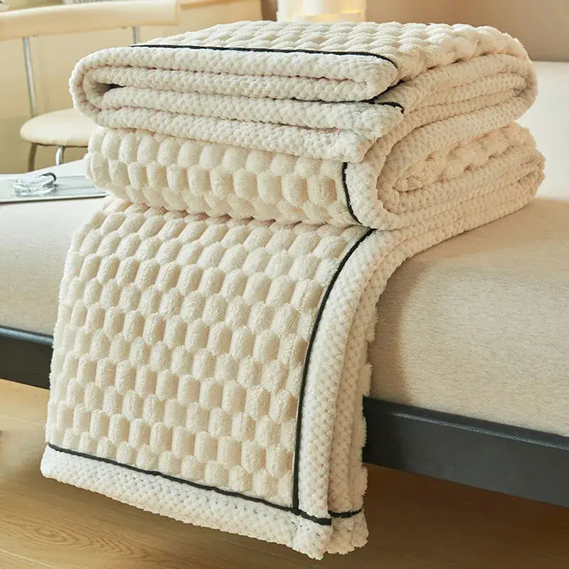Cream-colored coral fleece blanket with textured quilted pattern and black piping edge for bedroom throw use