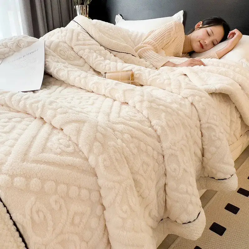 Cream-colored coral fleece blanket with raised intricate pattern and black trim chunky knit bedroom throw