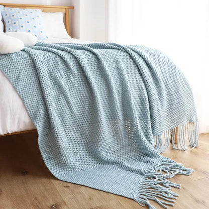 A soft light blue knitted leisure blanket throw with a textured waffle pattern and tassels for bedroom decorbites decor