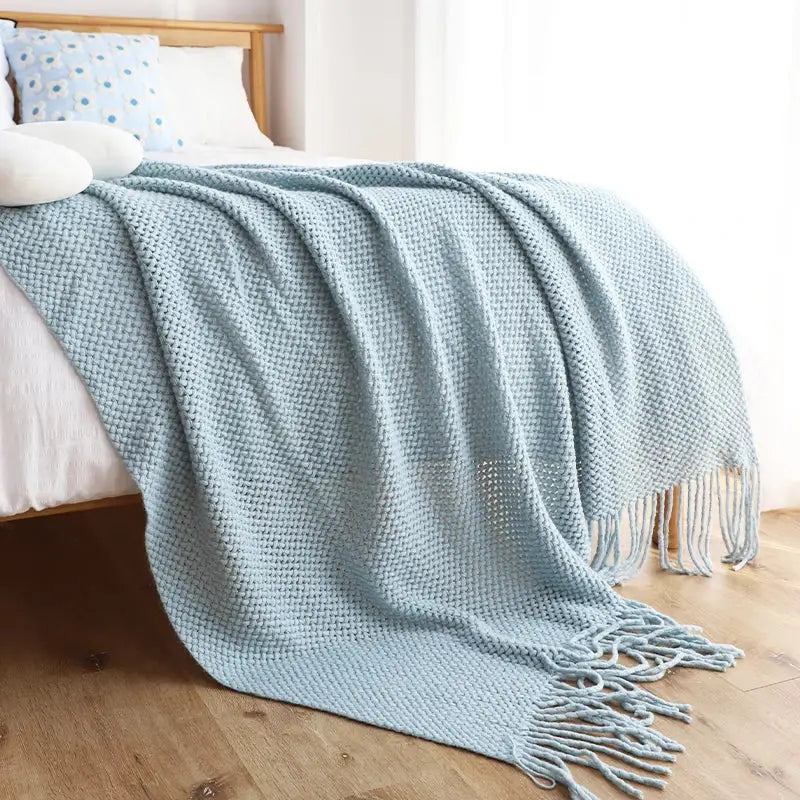 A soft light blue decorbites knitted leisure blanket with waffle pattern and tassels for bedroom and living room decor