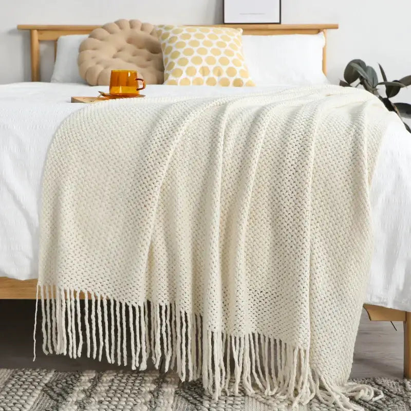 Cream-colored chunky knitted leisure blanket throw with textured weave and long fringe for bedroom and living room decorbites decor