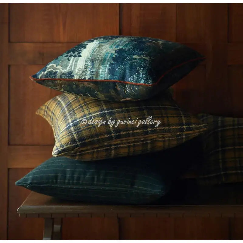 Stacked decorative pillow covers in navy blue, mustard plaid, and green pinstripe with embroidered decorbites circular swallows detail