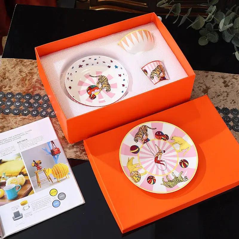 Vibrant orange gift box with decorbites circus troup kids pink and white ceramic tableware set featuring tiger and acrobat designs