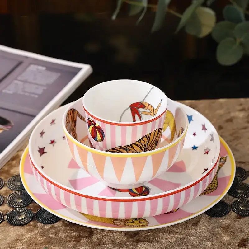 A vibrant pink and white ceramic tableware set with circus troup kids whimsical tiger and acrobat illustrations by decorbites