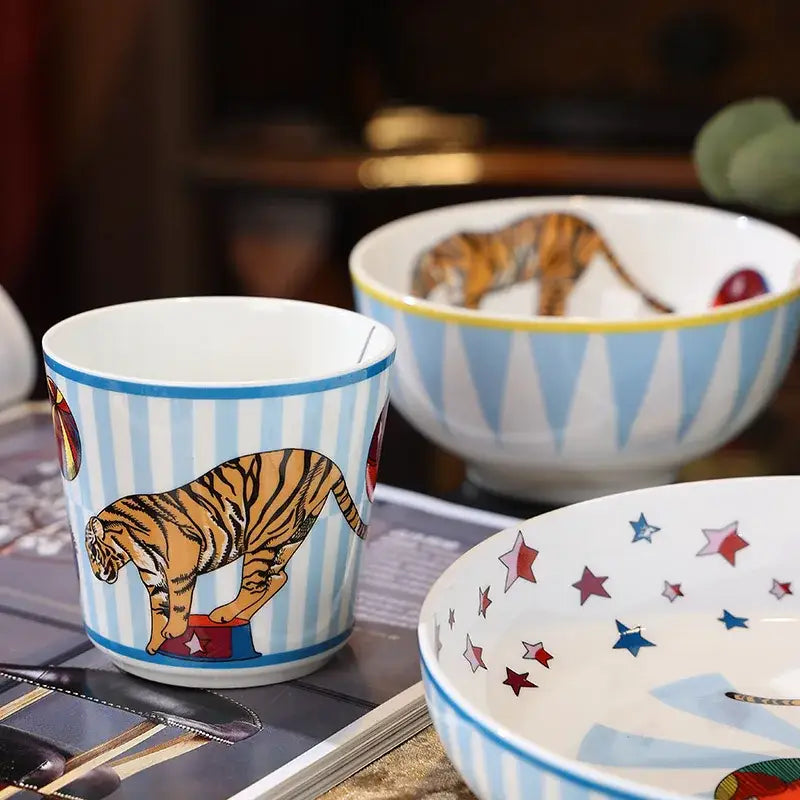 A ceramic cup from decorbites circus troup kids tableware set featuring blue and white stripes with an orange tiger design