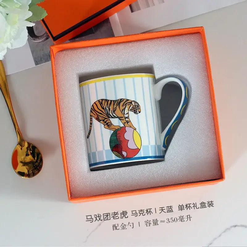 A white ceramic mug from decorbites circus troup kids tableware set with a vibrant tiger balancing on a colorful ball