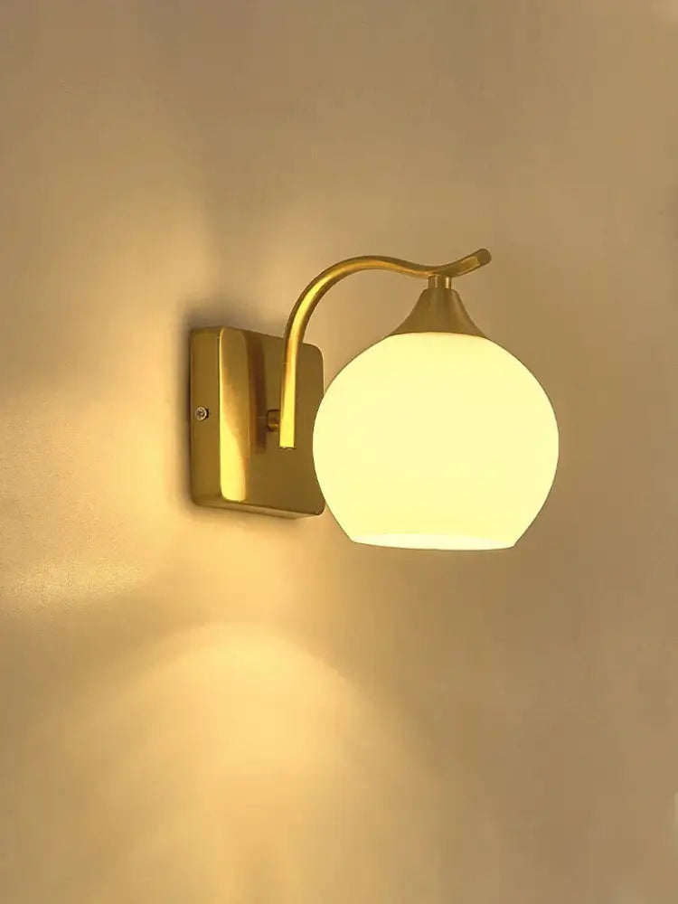 Classic brass glass wall sconce with gold-toned curved arm and frosted globe shade for bedroom decorbites brass glass wall