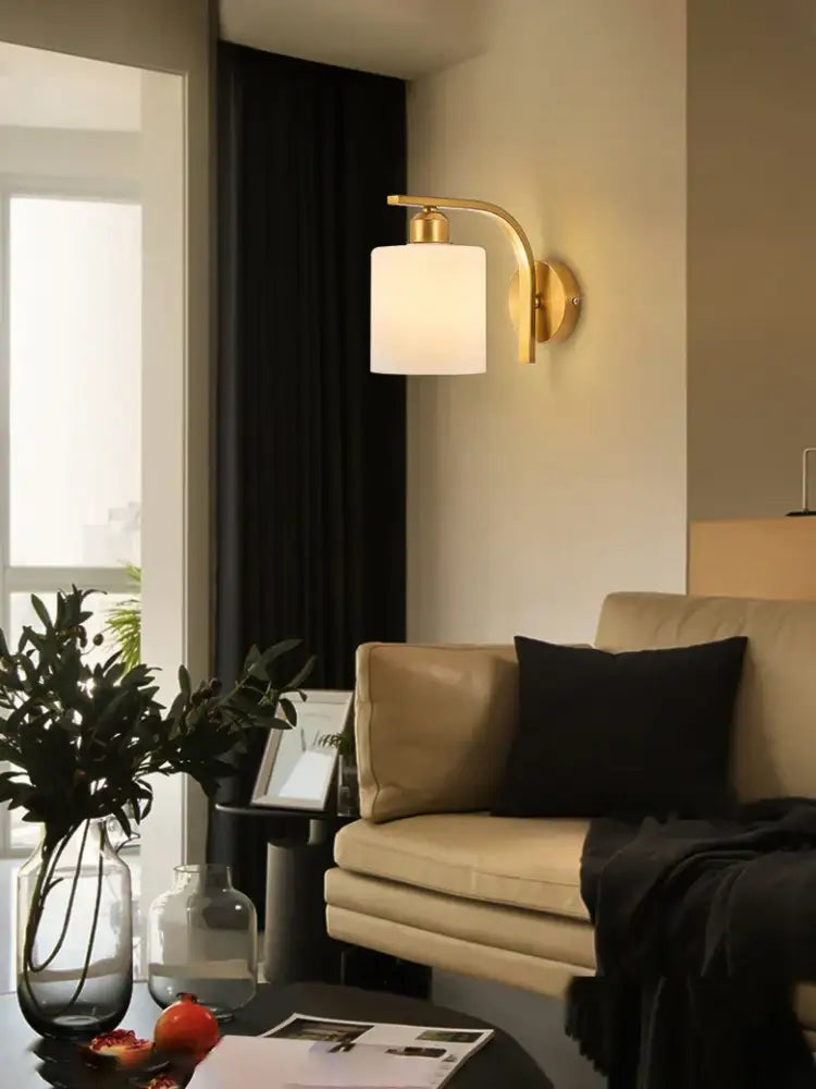 Classic brass glass wall sconce with gold-toned metal and a cylindrical frosted glass shade for bedroom decorbites brass glass