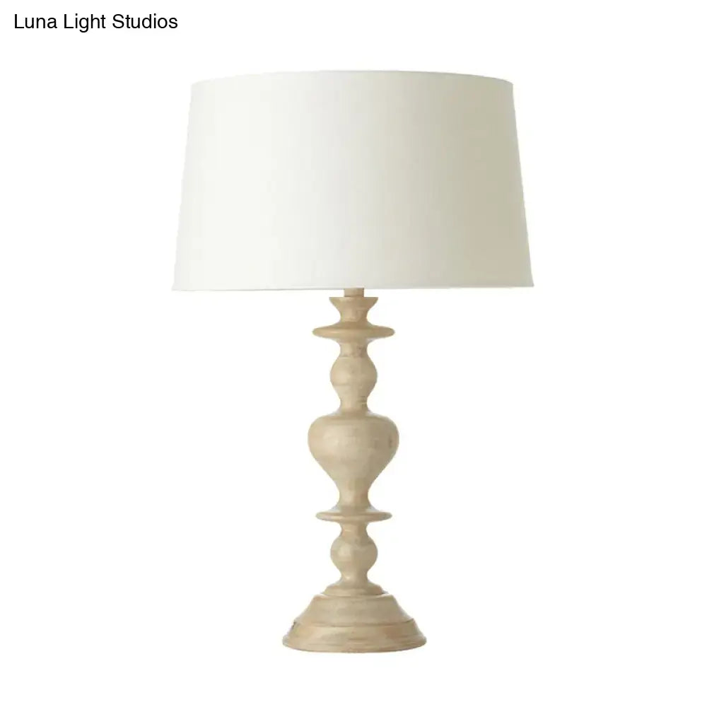 A cream-colored decorbites white resin base fabric nightstand lamp with classic tapered design for 220v-240v use