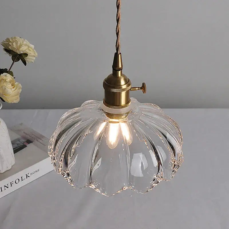 Clear glass pendant light with brass-finished socket and twisted cord in classic glass style for dining room use