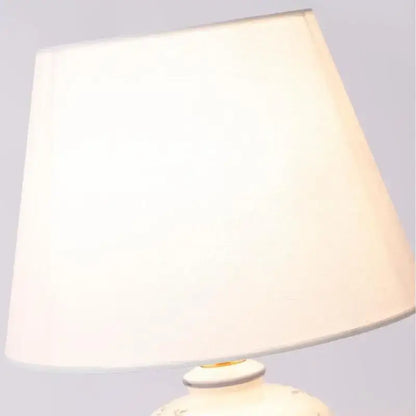 Cream-colored fabric lampshade with a soft tapered design on a classic white and black porcelain table lamp for living room decor